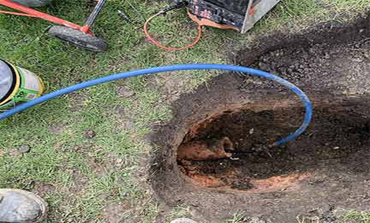 Blue pipe inserted into dug-up hole for underground plumbing repair