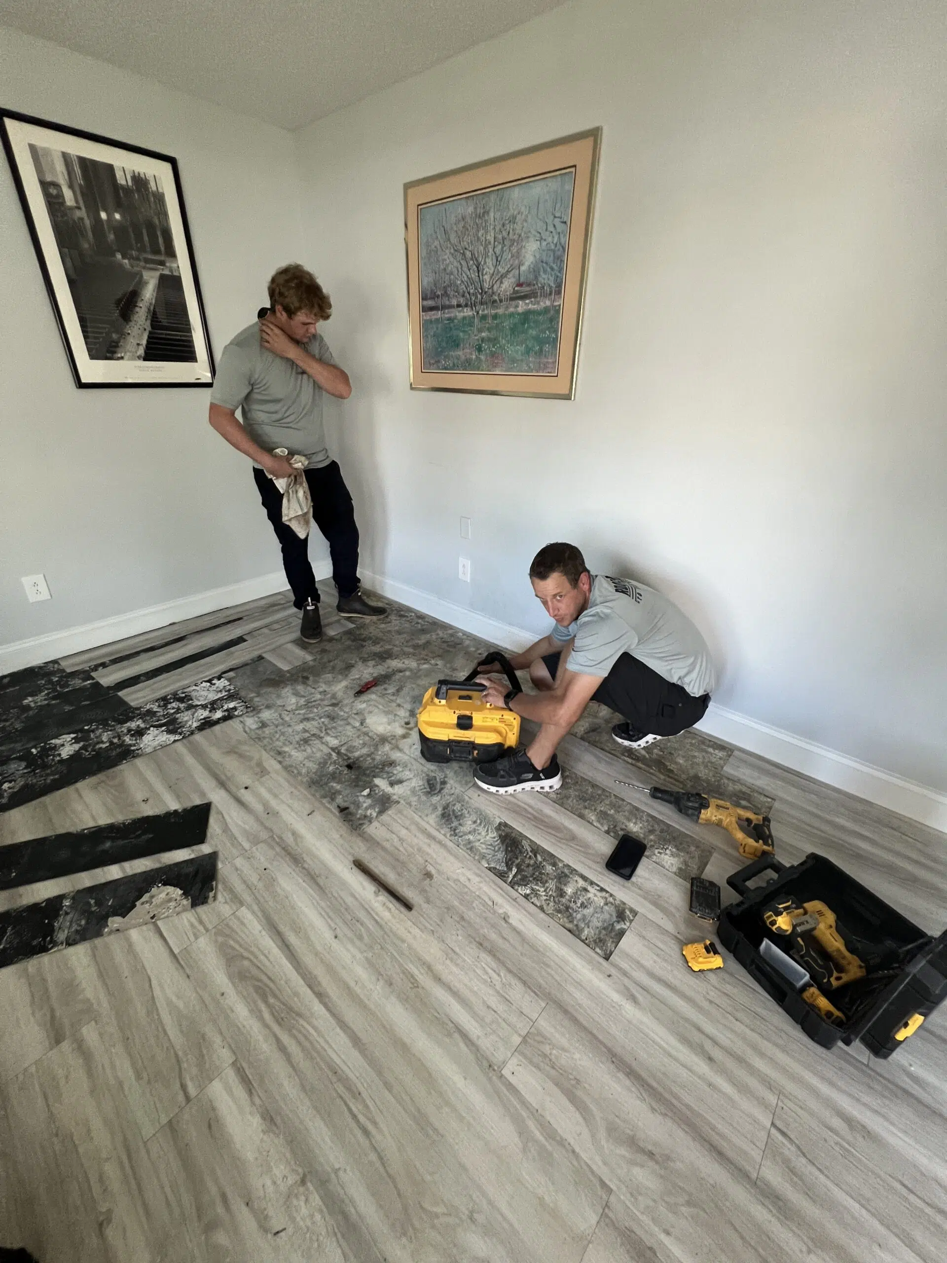 2 plumbing technicians working on repairing a slab leak located in the floor of an apartment living room.
