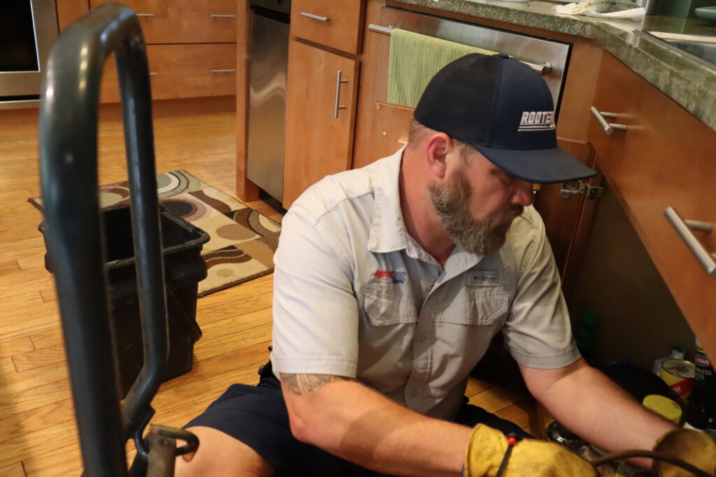 Plumber repairing an under-sink plumbing issue in a Mount Pleasant, SC home.