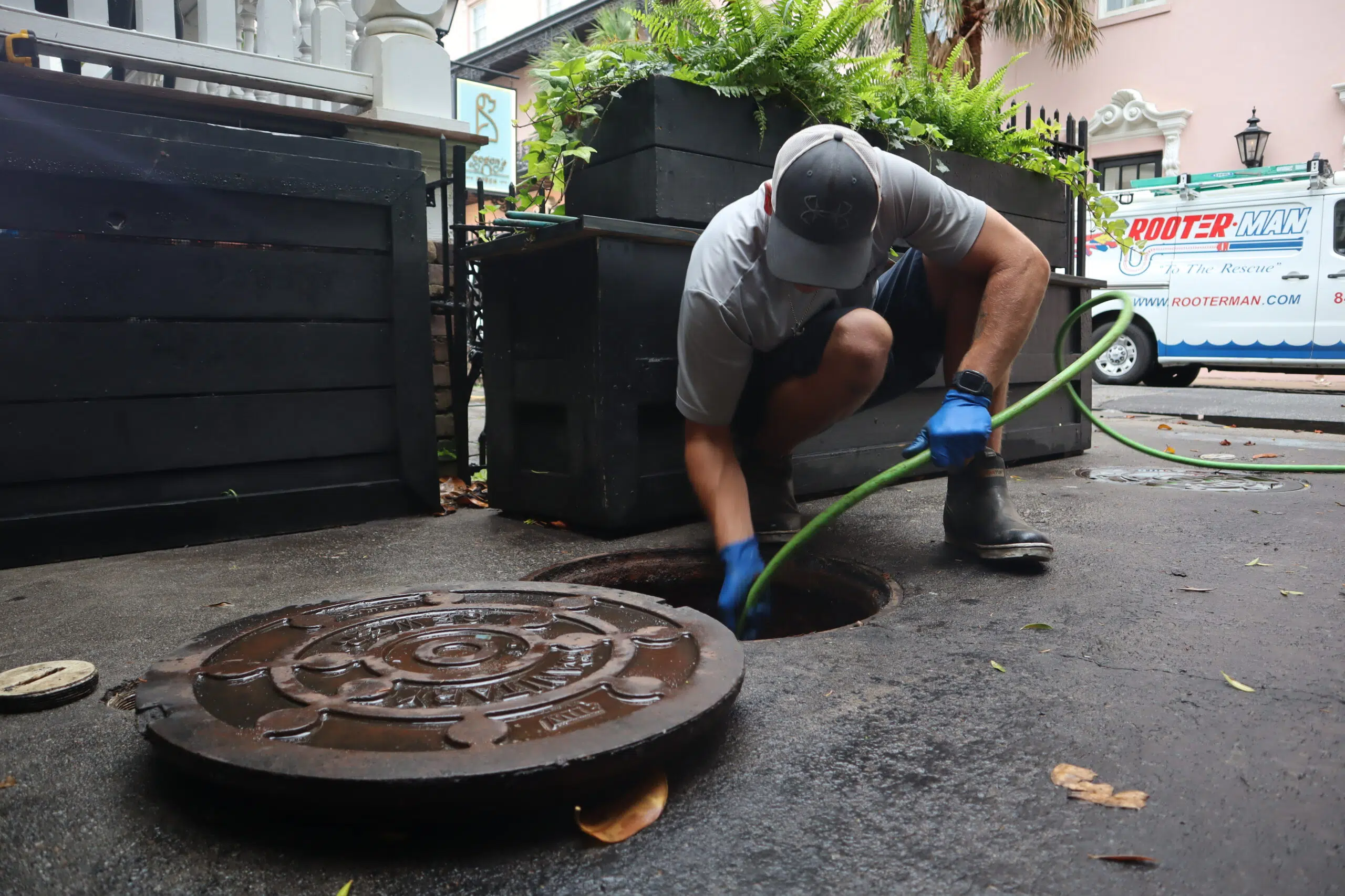 Rooter Man technician performing hydro jetting through an open manhole in Downtown Charleston SC to clear a commercial drain line