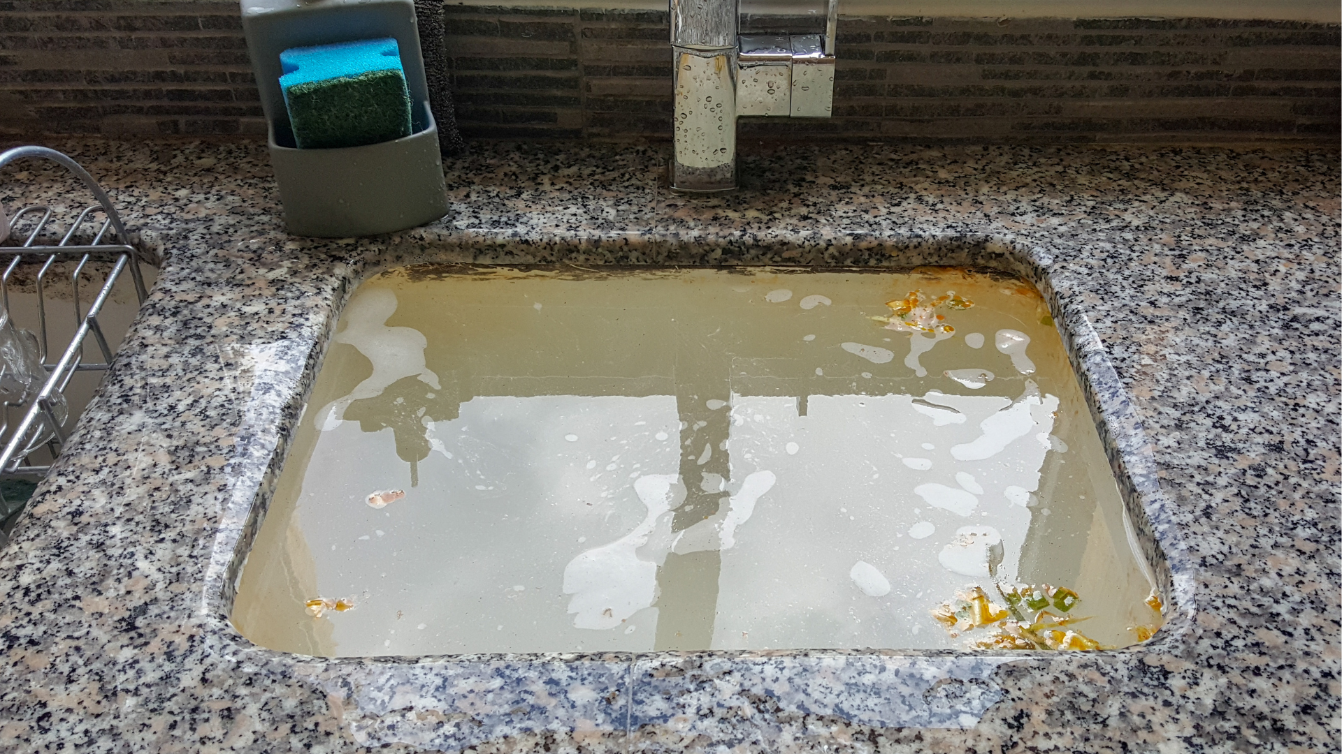 a kitchen sink filled with dirty backed up water.
